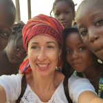 White woman in turban is surrounded by smiling African children