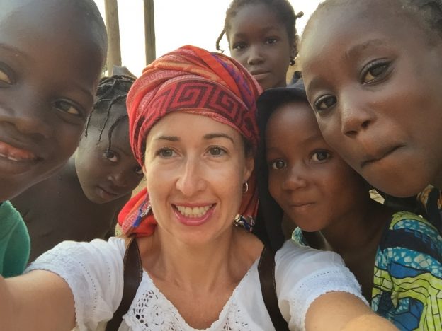 White woman in turban is surrounded by smiling African children